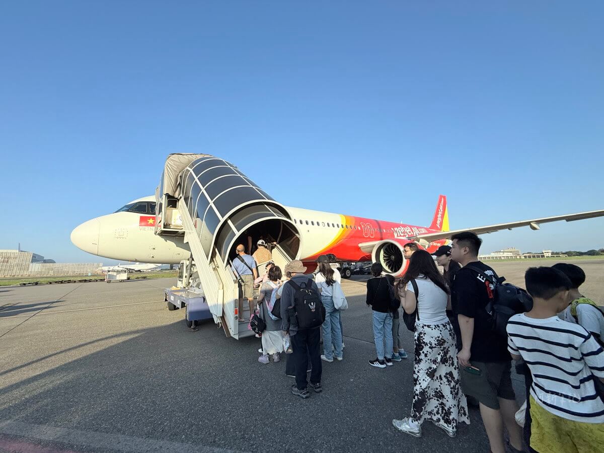 桃園機場機坪上旅客排隊走樓梯登上越捷航空紅色塗裝客機